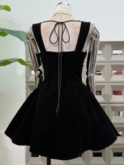 Detail view of embellished straps and neckline trim on a square-neck velvet-look mini dress against a clean studio backdrop.