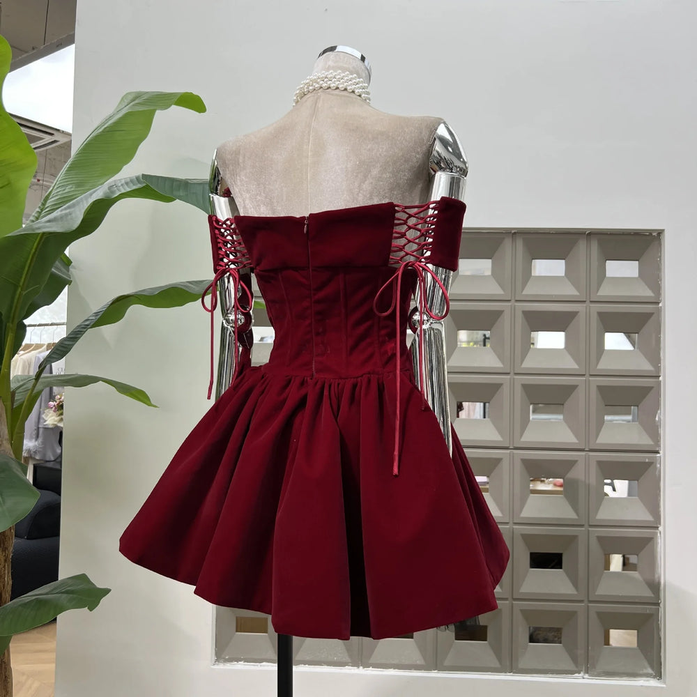 Hem detail showing lace trim beneath the pleated puff skirt on a burgundy velvet corset mini dress.