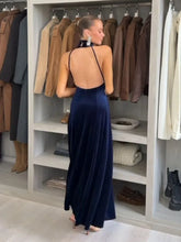 Woman wearing a velvet open-back halter maxi dress in a wardrobe setting
