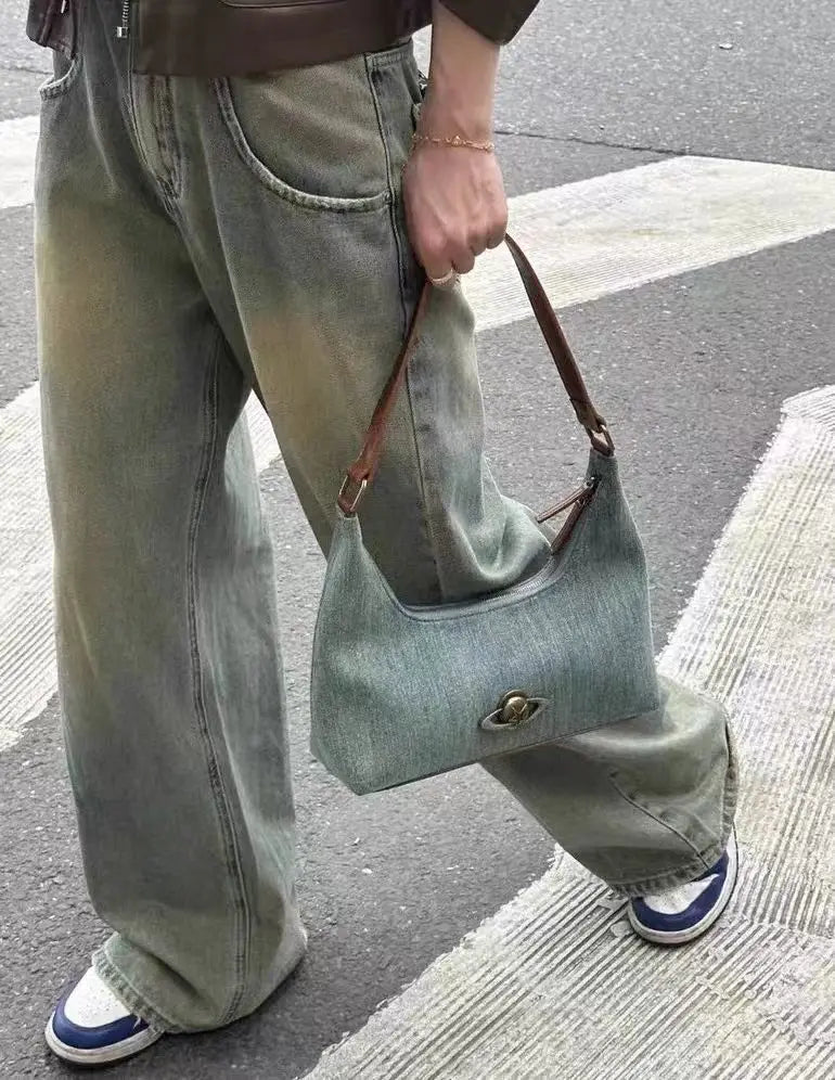Person holding a  soft-structured Y2K denim shoulder bag on  a street