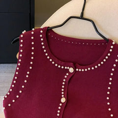 Maroon cardigan with pearl embellishments on a hanger