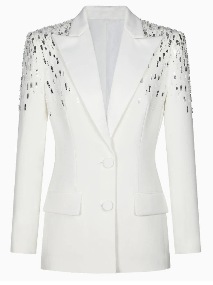 Close-up of sequin patchwork along the shoulder of a white tailored blazer, highlighting contrast and texture.