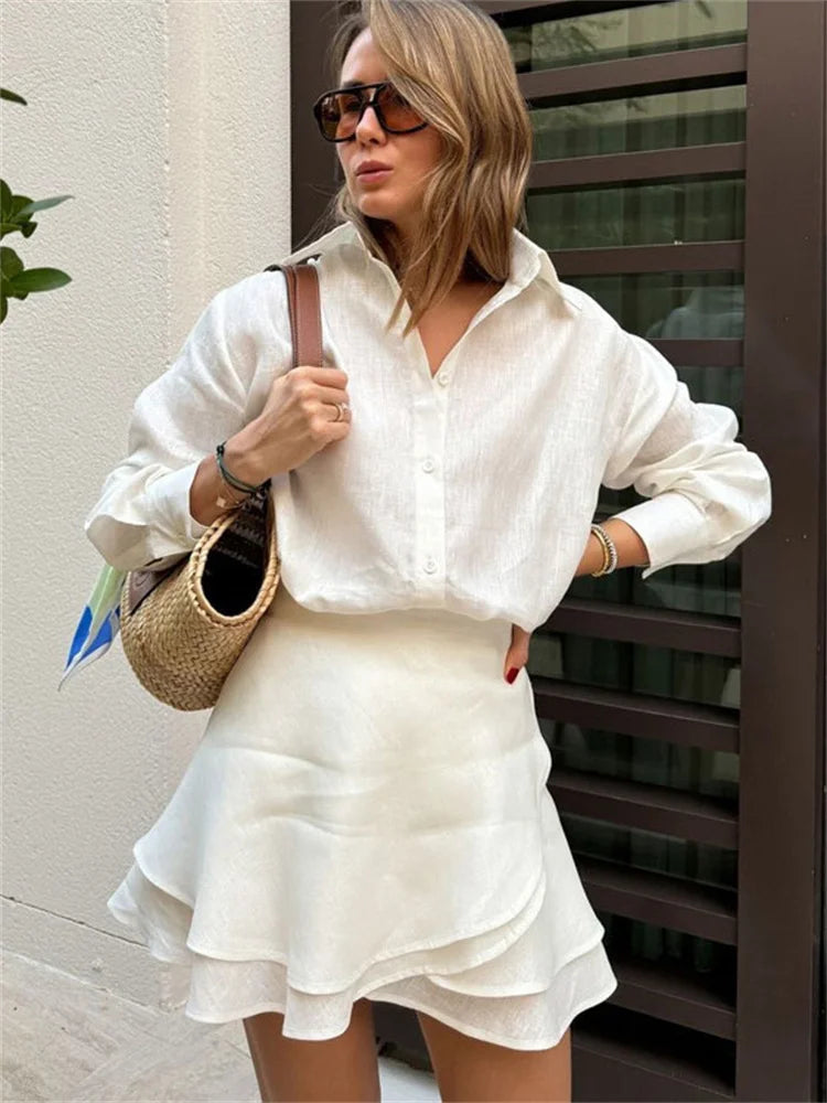 Woman in a white co-ord shirt and ruffle skirt styled with straw bag