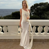Woman wearing a white diagonal neckline evening dress on a balcony