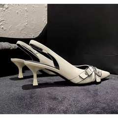 Pair of beige high-heeled shoes for formal party wear with a buckle on a textured surface.