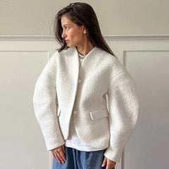 A woman wearing a white faux fur cardigan jacket with a V-neckline.