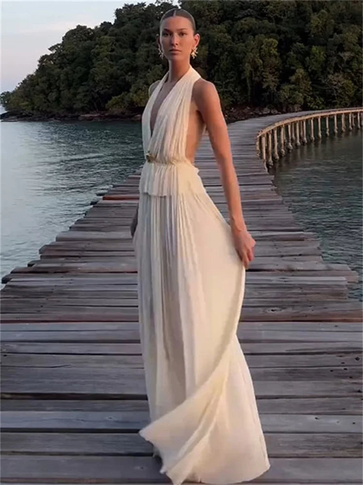 Woman wearing white halter backless set on a dock at sunset