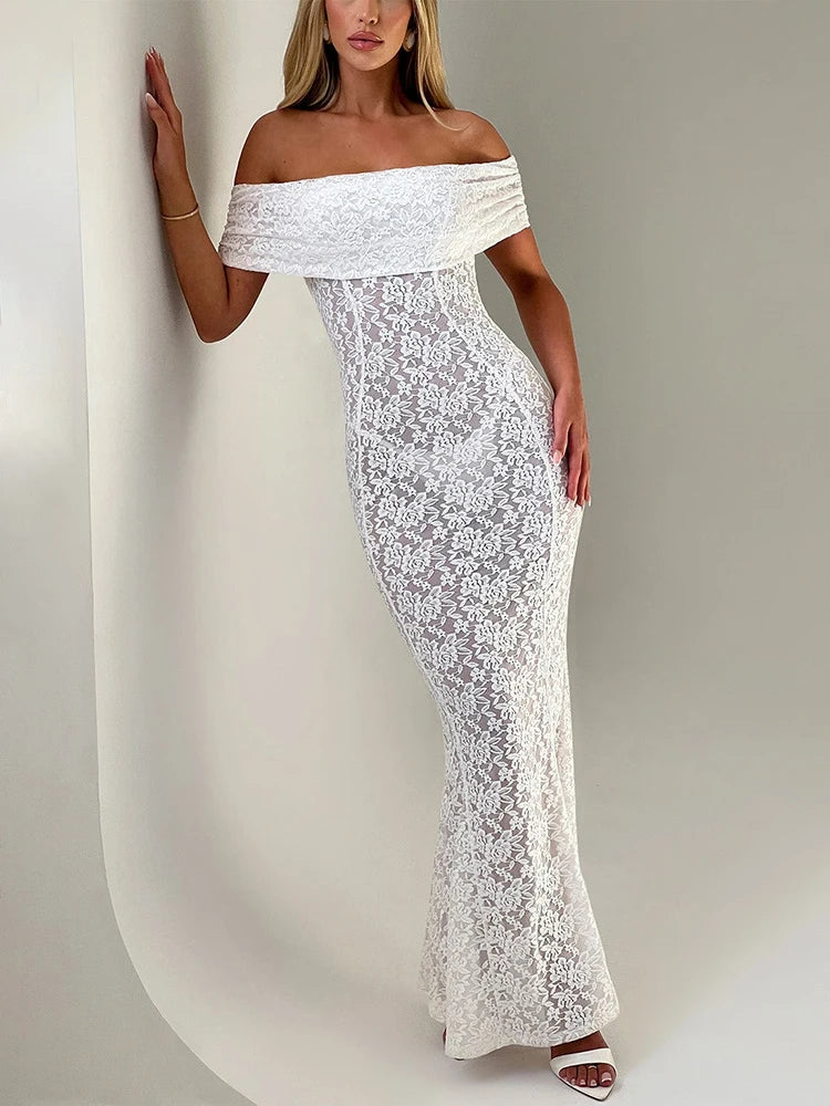 Woman wearing a white lace off-shoulder dress against a plain background