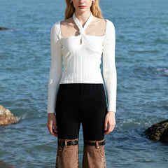 Front view shows the slash-neck frame and halter twist detail, paired with high-waist trousers for a clean, modern silhouette.