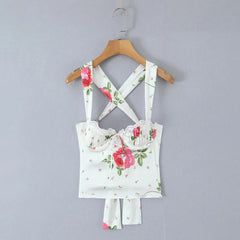 Floral-patterned top with straps on a wooden hanger against a gray background