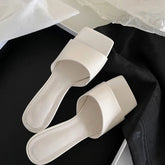 White square toe wedge heel slides placed on black fabric