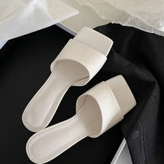 White square toe wedge heel slides placed on black fabric