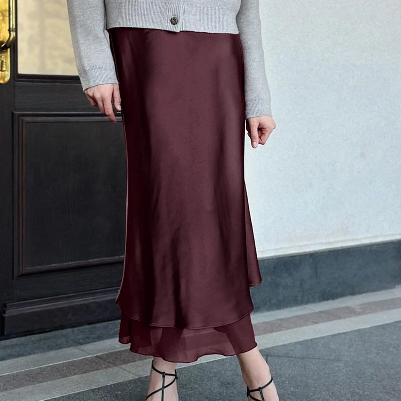 Person wearing a wine i satin midi skirt styled for office and evening wear in an indoor setting