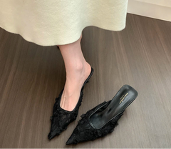 Close-up of floral lace detailing on black mule heels