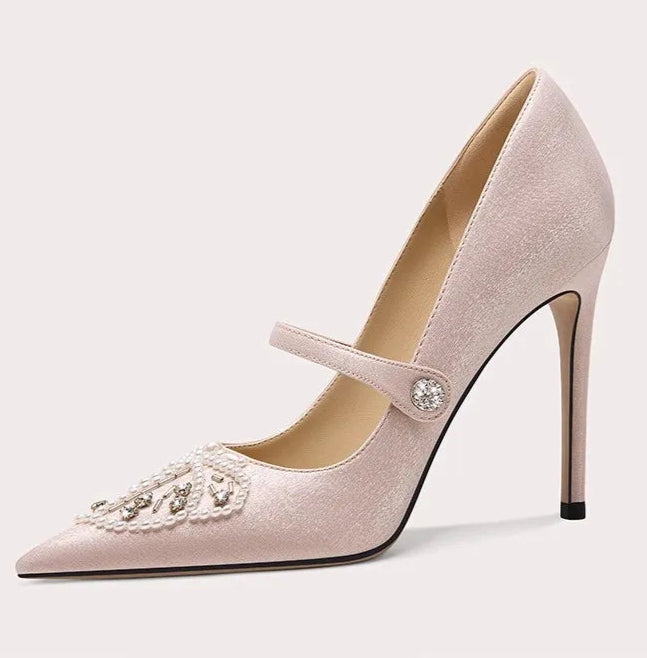 Pink high-heeled shoe with decorative strap on a light gray background