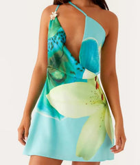 Woman wearing a sleeveless halter dress in green and blue tropical pattern with a white background