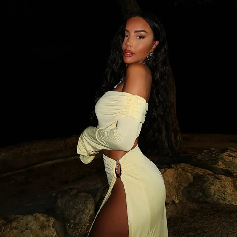 Woman in a f apricot beachwear set with long skirt and fitted top standing against a dark background