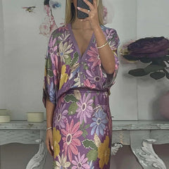 Person wearing a floral satin ankle-length skirt with an elastic waist, with a blurred background.