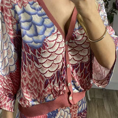 Close-up of a Person wearing a colourful patterned dress with a red strap over a neutral background