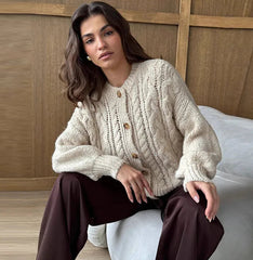 Close-up of the cardigan’s cable-knit texture and wooden-look buttons, highlighting the chunky stitch pattern and clean placket finish.