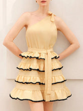 Yellow one-shoulder mini dress with layered ruffles and black trim on a plain background