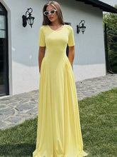Woman in yellow short sleeve maxi dress standing on a stone path