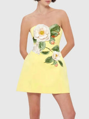 Yellow strapless mini dress with white floral embroidery on a plain background