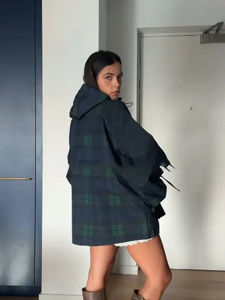 Three-quarter view showing the hood and higher neckline when zipped, styled with bare legs and boots for a bold winter look.