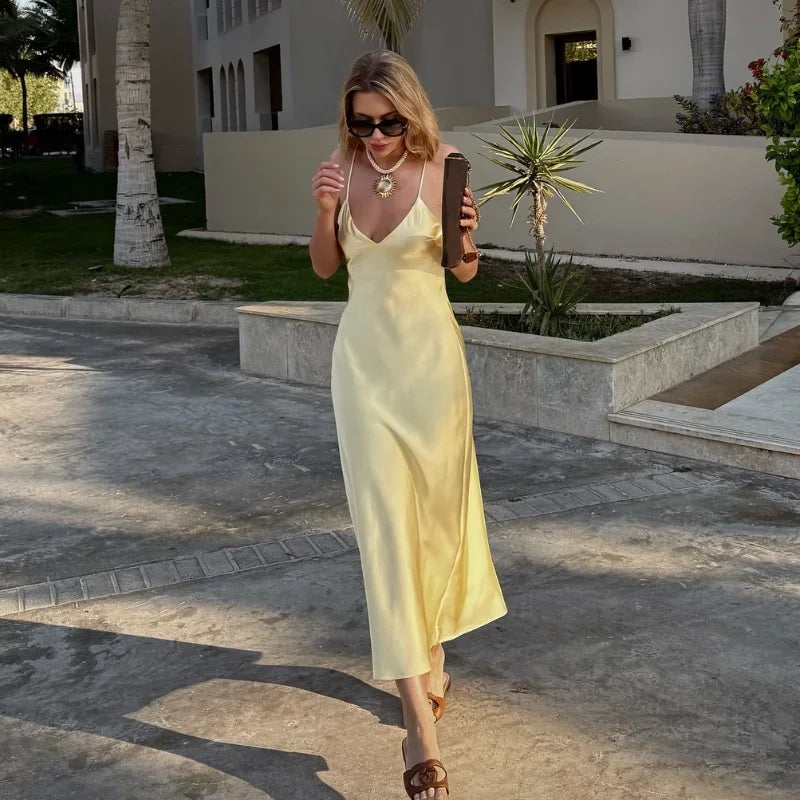 Woman in a yellow dress holding a brown bag outdoors.