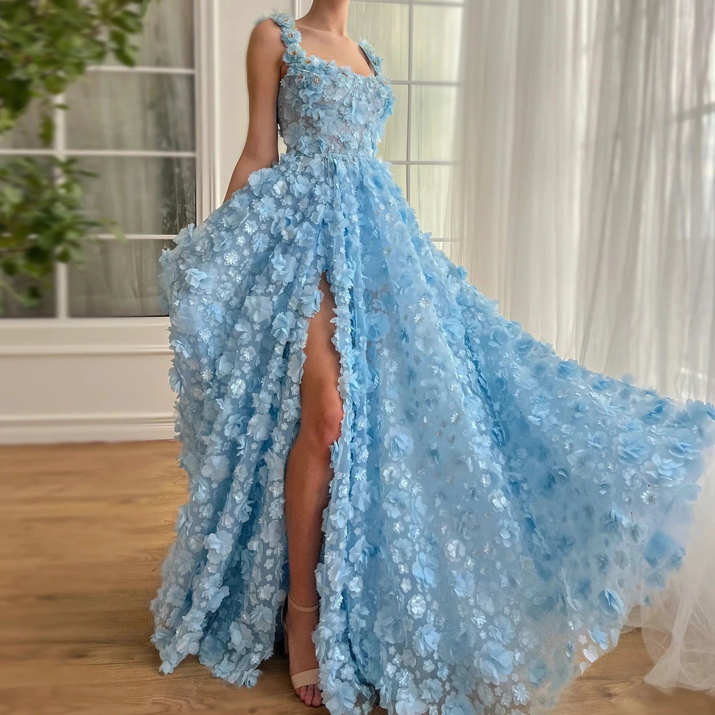 A woman wearing a lilac evening gown with 3D embroidered flowers and a high slit.