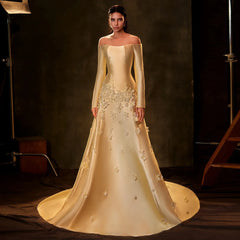 Woman wearing a  3D flower off shoulder evening dress in yellow for a formal event with floral details in a studio setting.