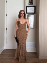 Woman posing indoors in a polka dot floral print maxi dress holding a clutch.