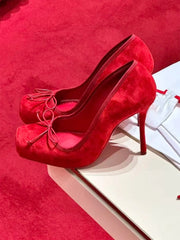Red high-heeled shoes on a red surface with a white box.
