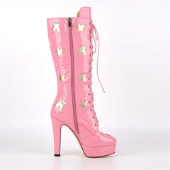 Close-up of pink patent leather knee-high lace-up boots showing butterfly cutouts