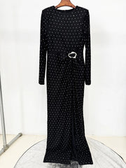Black dress with white polka dots on a hanger against a white background