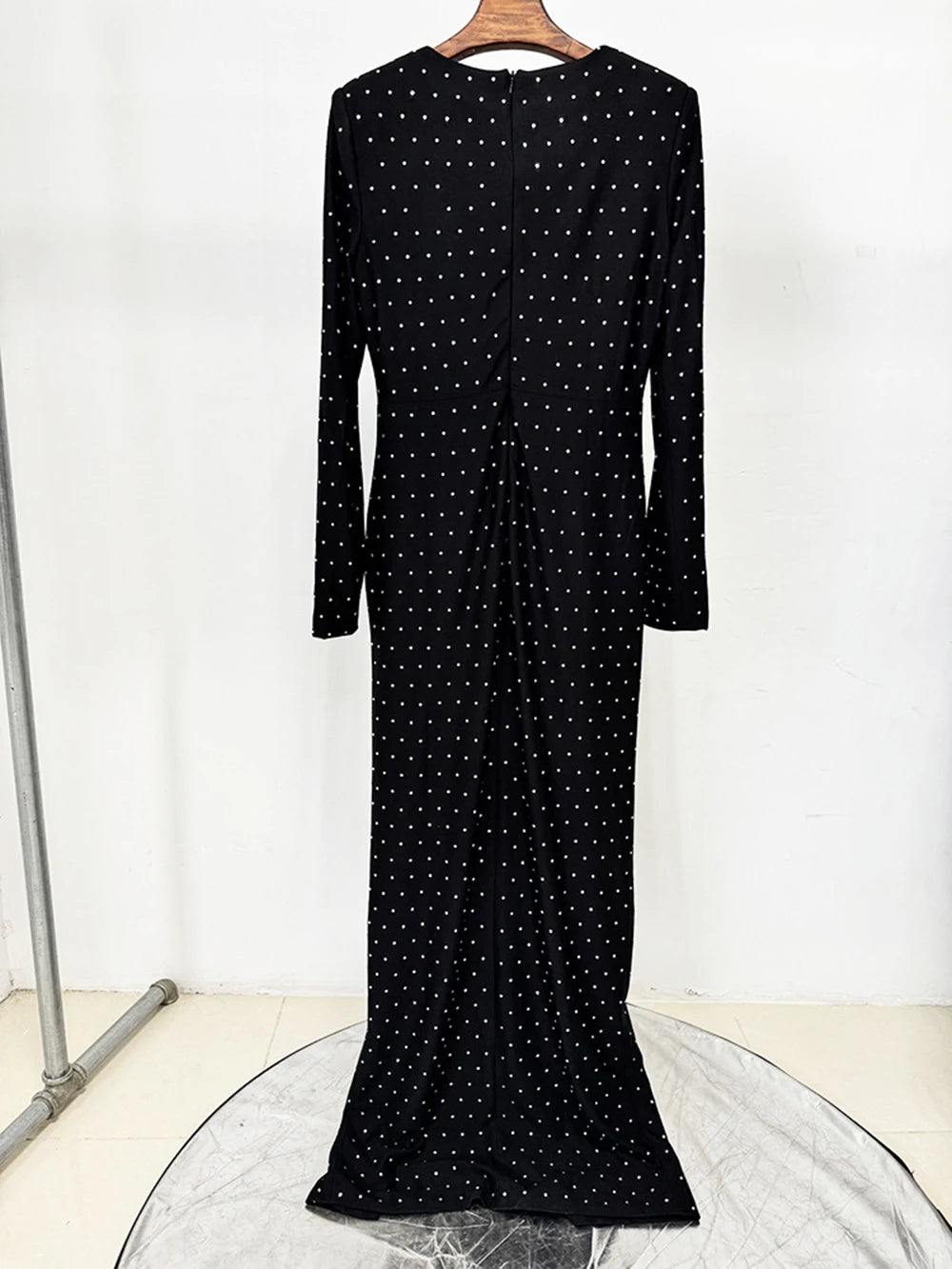 Black dress with white polka dots on a hanger against a white background