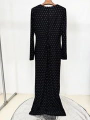 Black dress with white polka dots on a hanger against a white background