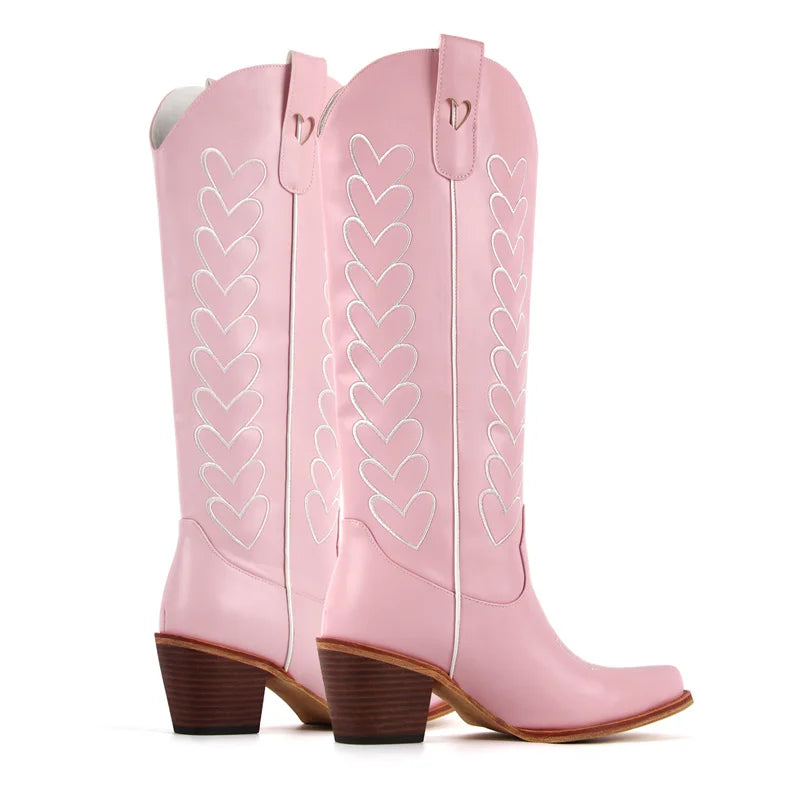 Pink cowboy boots with heart designs on a white background