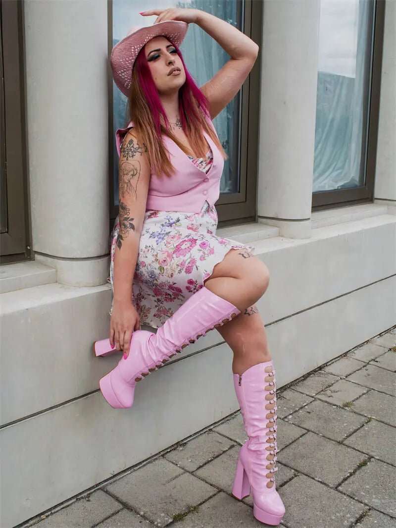 Model wearing pink patent lace-up platform knee-high boots with a floral skirt