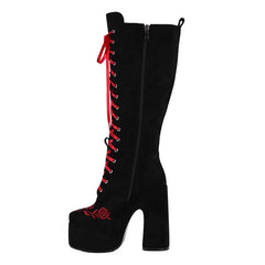 Black knee-high boot with red laces and rose design on a white background