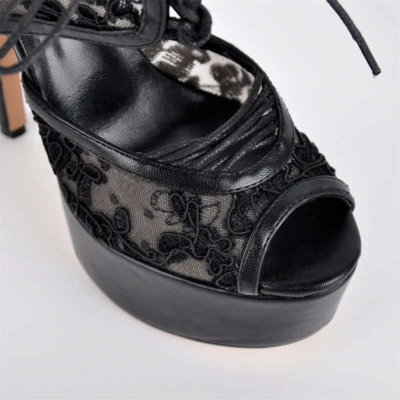 Black platform sandal with floral lace detailing on a light gray background