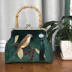 A close-up of an embroidered crossbody bag, showcasing the intricate bird design and fringe detailing.