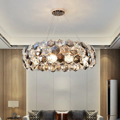 A stunning crystal chandelier with a wrought iron frame, hanging above a living room table.