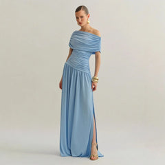 Woman wearing a light blue off-shoulder gown with a slit on a plain background