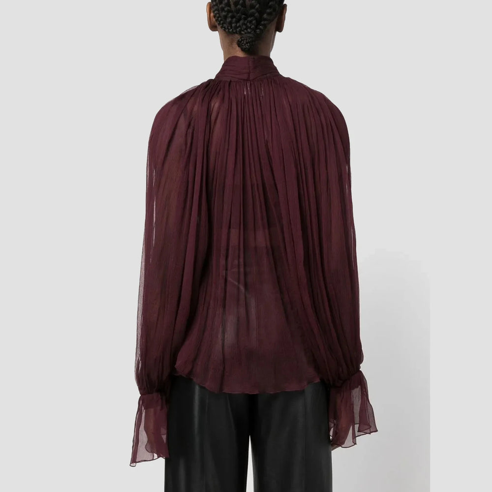Maroon sheer blouse worn by a person on a white background