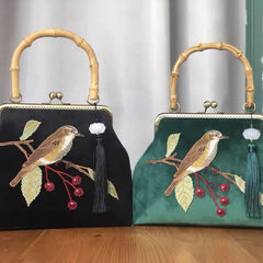 A close-up of an embroidered crossbody bag, showcasing the intricate bird design and fringe detailing .
