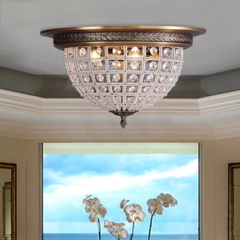 Decorative ceiling light fixture in a room with a window view of flowers and sky.