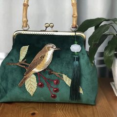 A close-up of an embroidered crossbody bag, showcasing the intricate bird design and fringe detailing.
