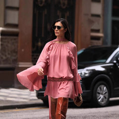 Woman in a pink dress and orange boots walking on a city street.