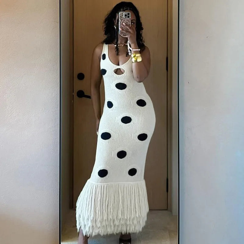 Person wearing a white dress with black polka dots and fringe details, standing in front of a mirror.